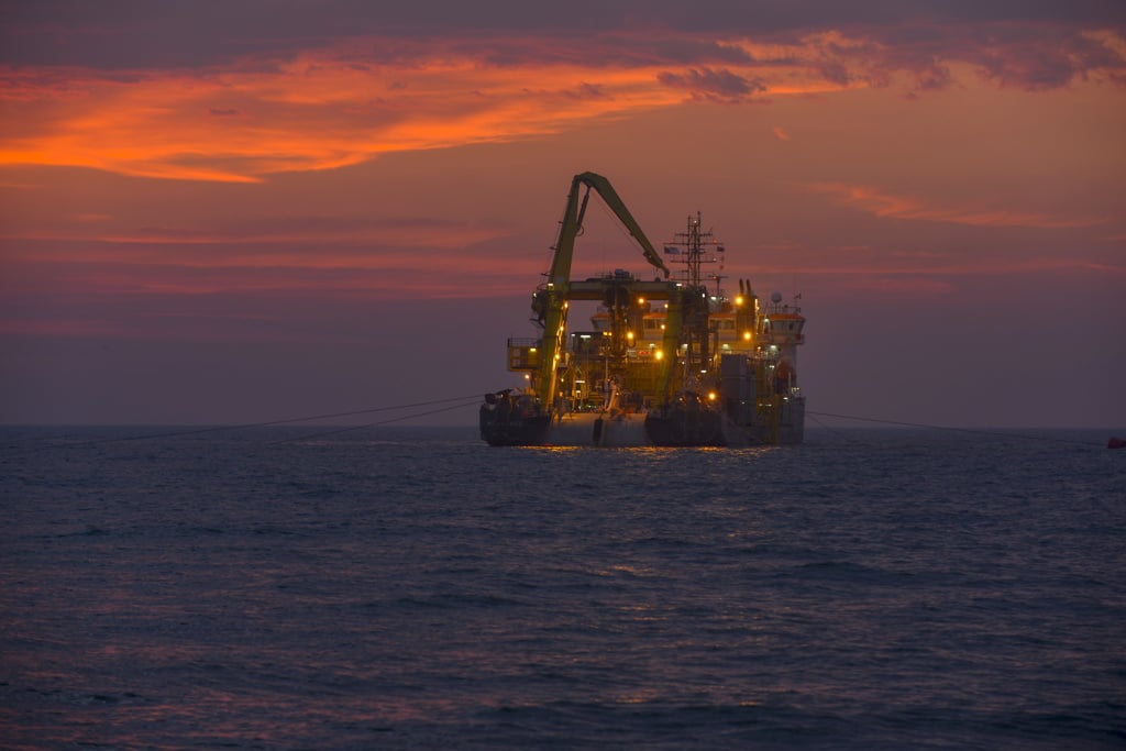 A photo of a Boskalis Subsea vessel working offshore at dusk