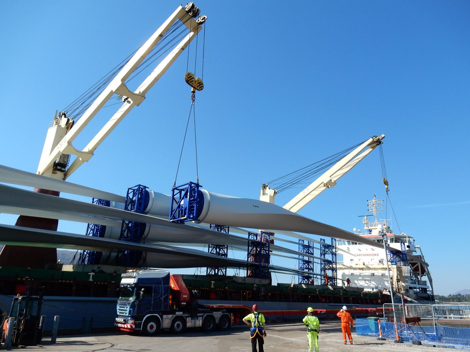 Wind turbine blades being loaded on a vessel