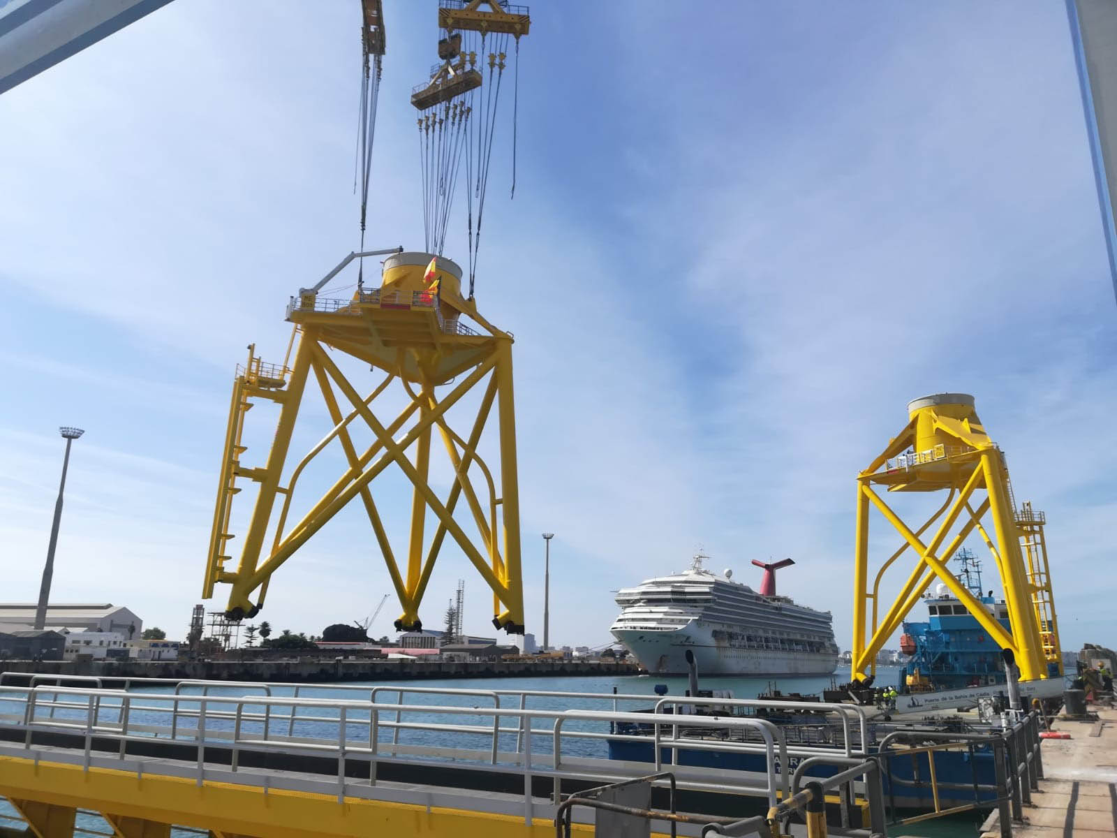 Upper part of jacket foundation being loaded out by a crane, with another one standing in the background