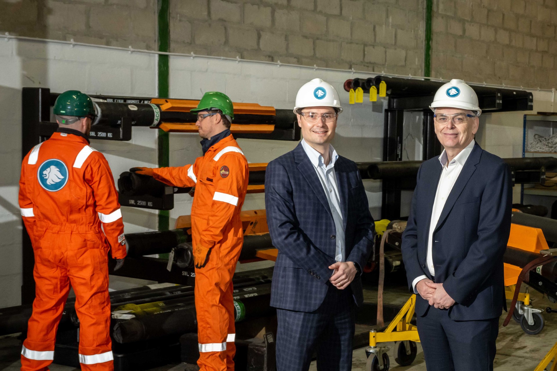 two men in suits standing in front of two men in work overalls