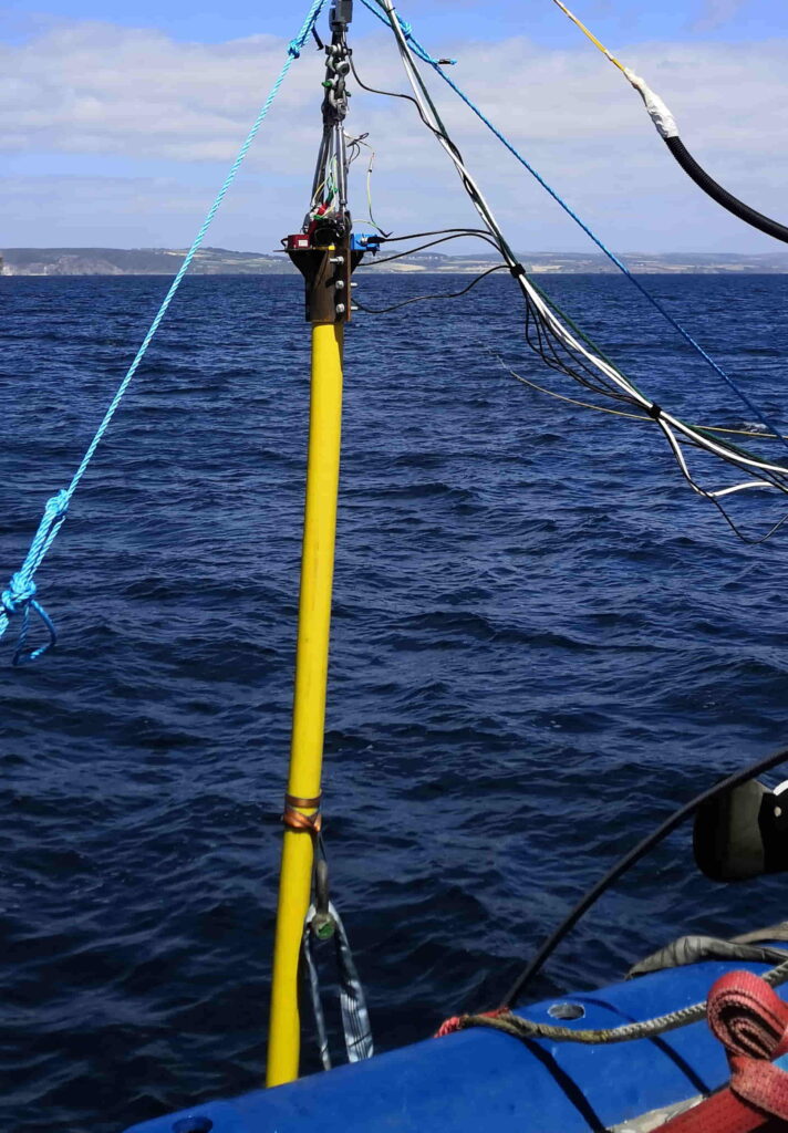 A photo of a yellow dynamic subsea cable being lowered into the sea from a vessel