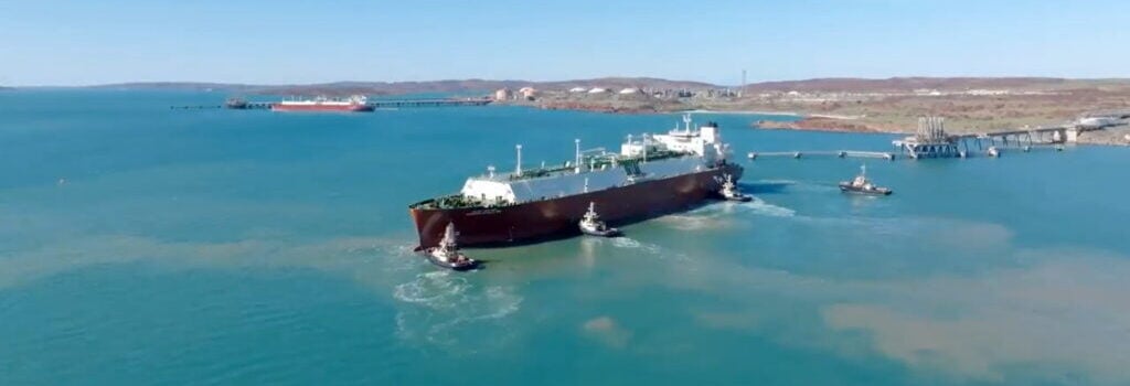 LNG vessel surrounded by four tugboats approaching a jetty