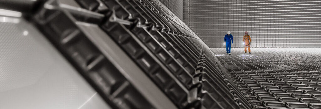 Two men inside a room with all surfaces covered in metal