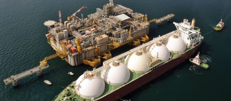 An offshore platform with a large vessel surrounded by several smaller vessels next to it