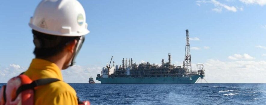 A man looking at a large vessel at sea