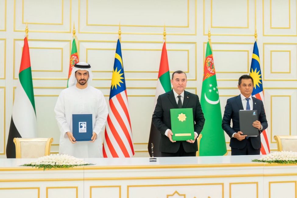 Three men standing behind a desk holding documents
