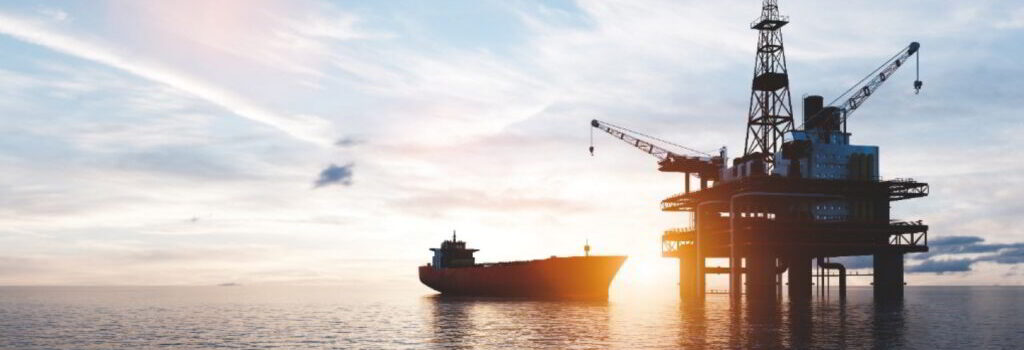 An offshore platform and a vessel next to it at sunset